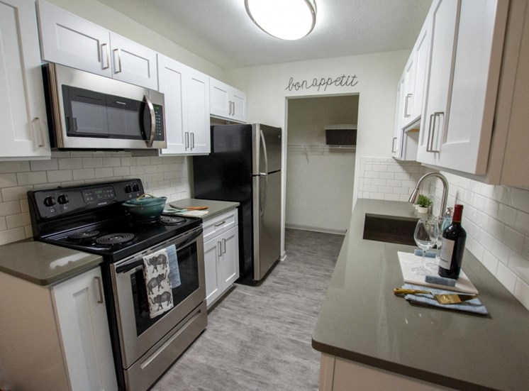 Cook in your gourmet kitchen at Icon Avondale. White cabinets, Sink, fridge, stainless steel appliances,
